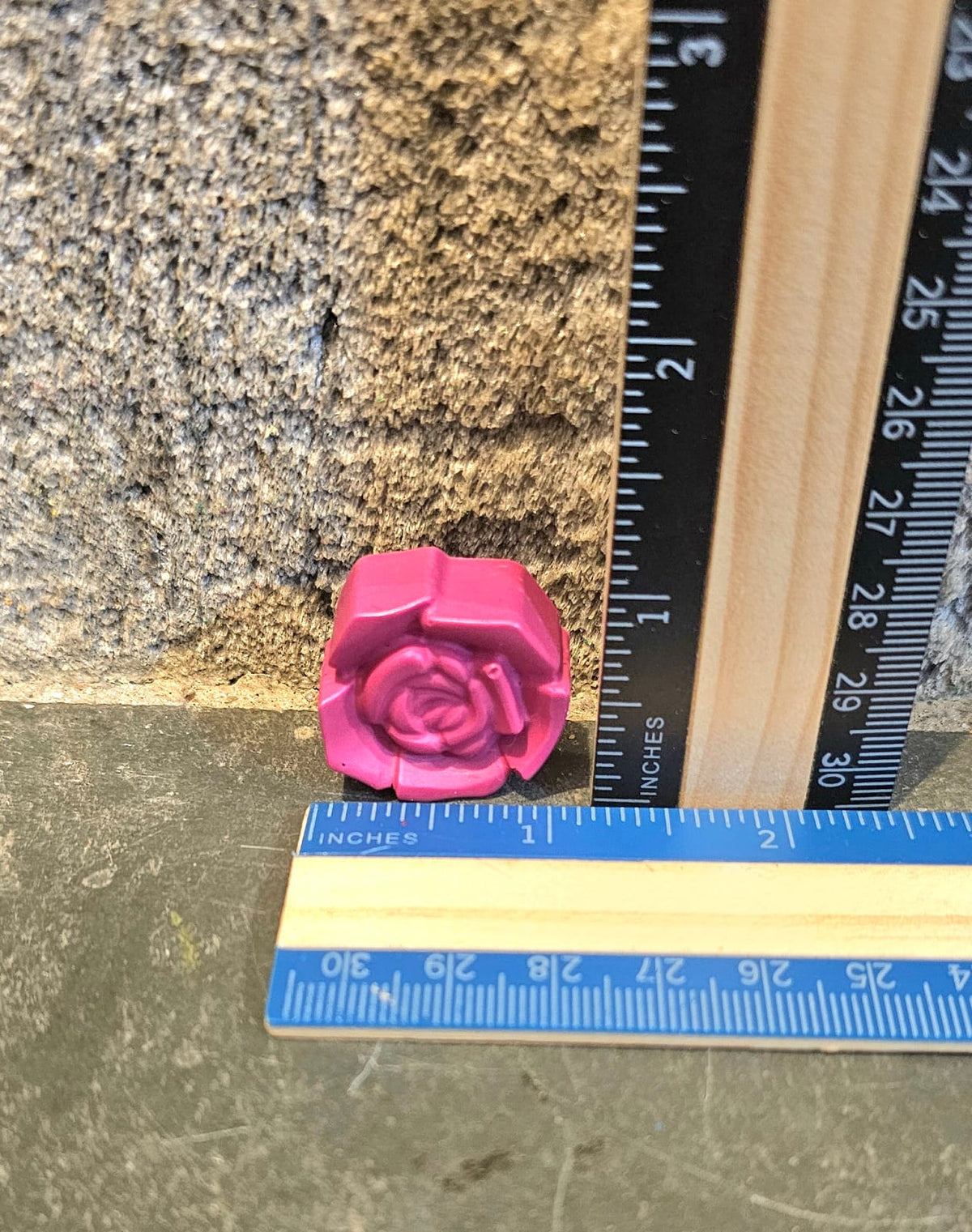 Pink rose shaped handmade crayon next to a ruler