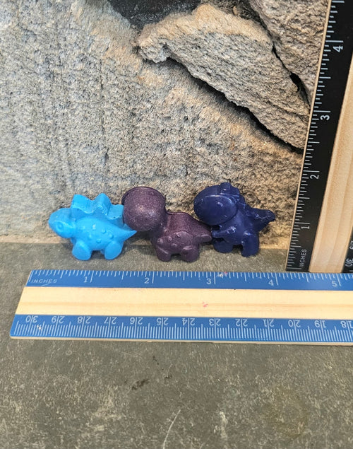 Set of three baby dinosaur shaped handmade crayons next to a ruler