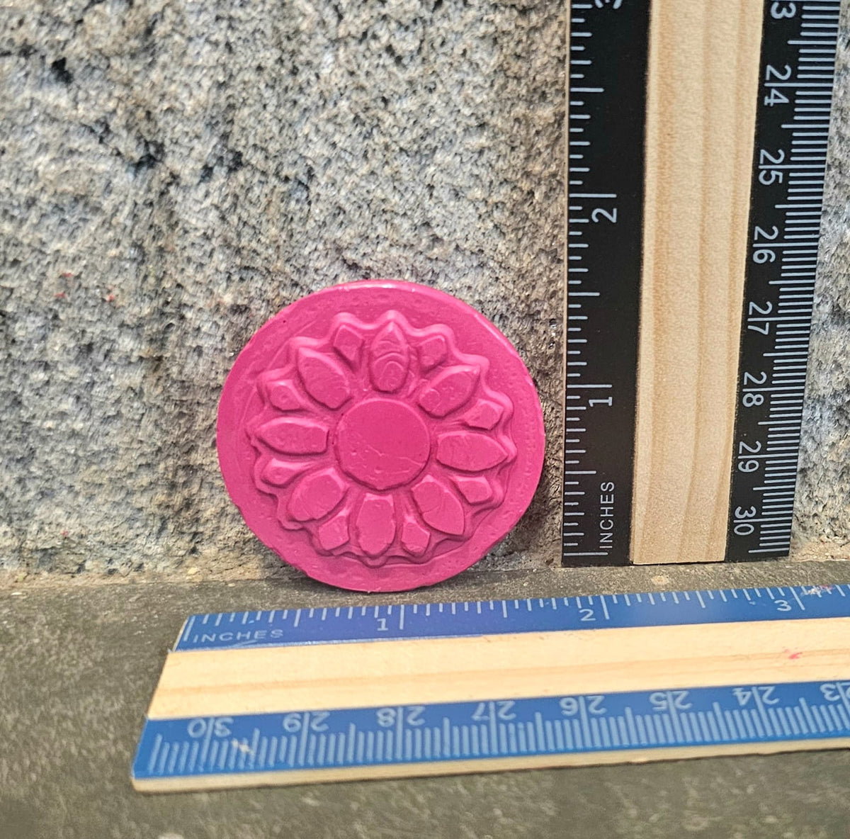 Pink flower medallion handmade crayon next to a ruler