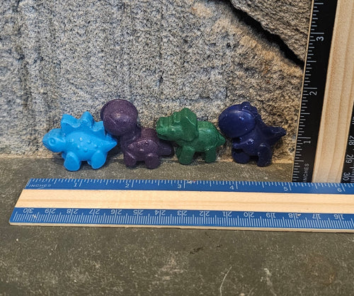 Set of four baby dinosaur shaped handmade crayons next to a ruler
