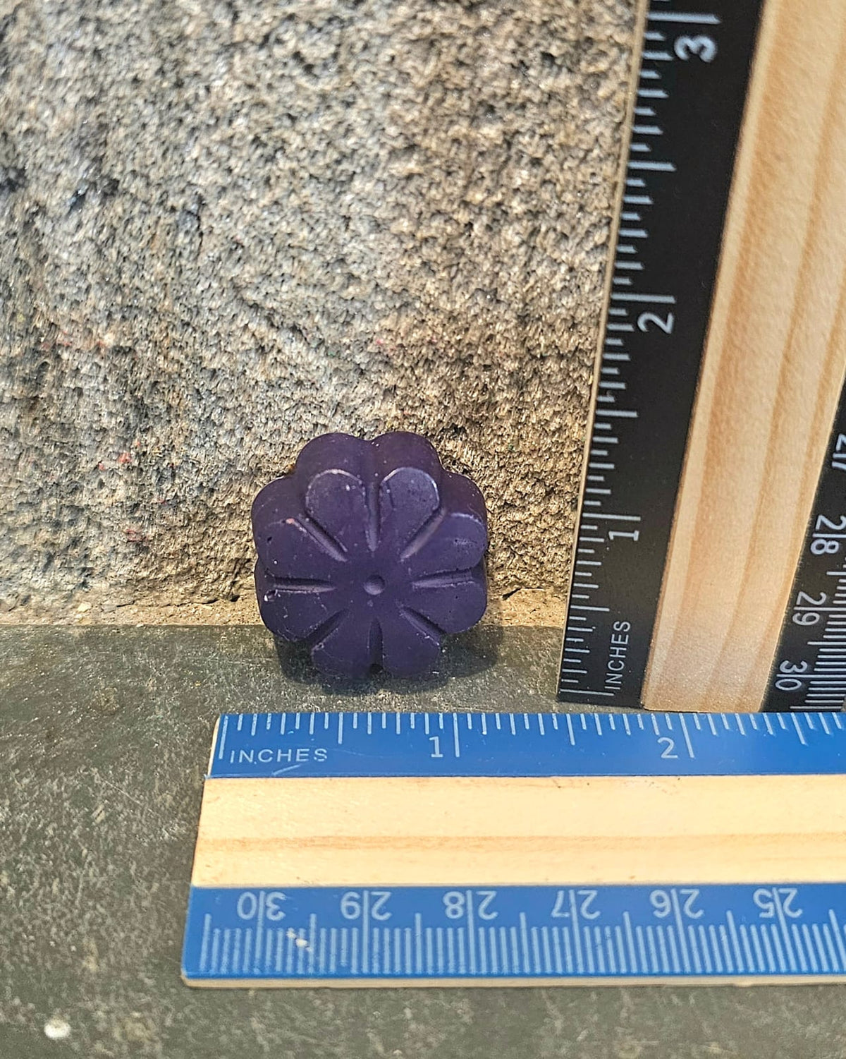 Purple flower shaped handmade crayon next to a ruler