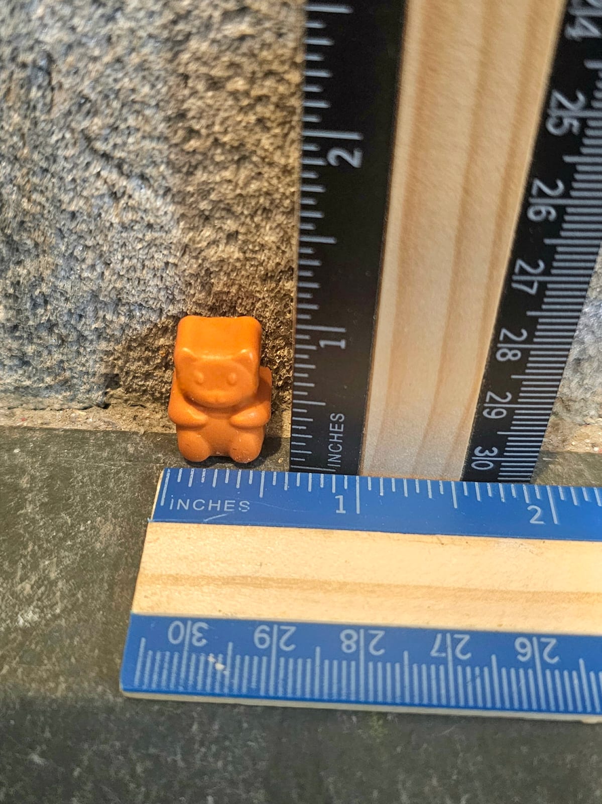 Orange mini teddy bear shaped handmade crayon next to a ruler
