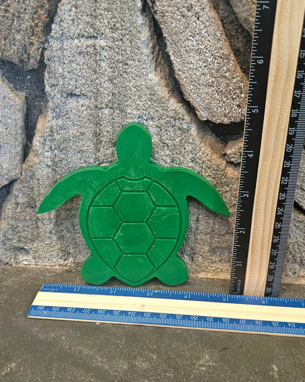 Large green sea turtle shaped handmade crayon next to a ruler