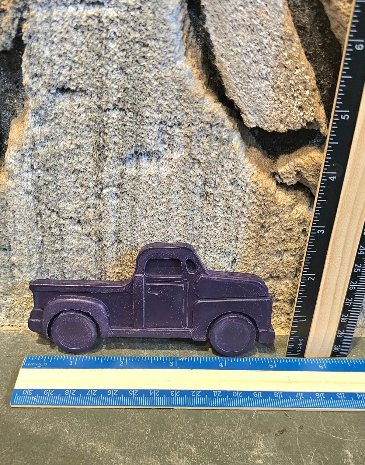 Purple vintage pickup truck shaped handmade crayon next to a ruler